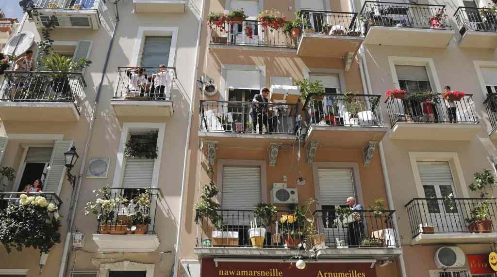 Façade d'immeuble avec balcons fleuris et personnes