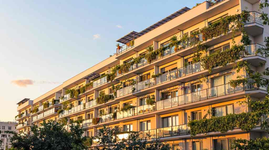 Apartment building with green balconies at sunset